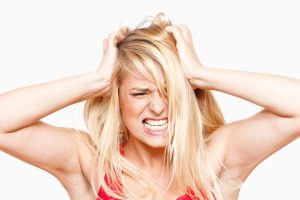 angry, frustrated girl with hands in her hair screaming - isolated on white